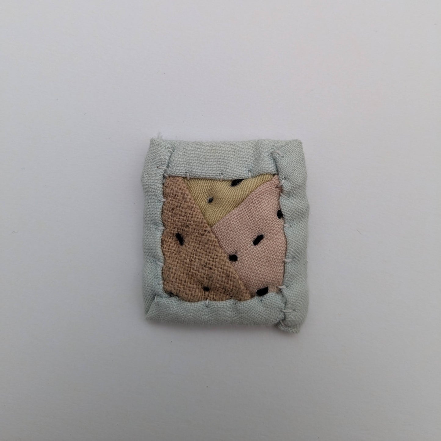 Square quilted magnet in pink, yellow, and blue.