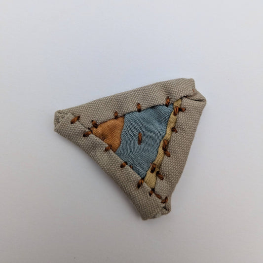 Triangular quilted magnet in rust, blue, yellow and brown