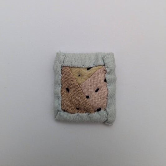 Square quilted magnet in pink, yellow, and blue.