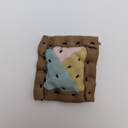 Square patchwork magnet in brown, blue, pink, and yellow