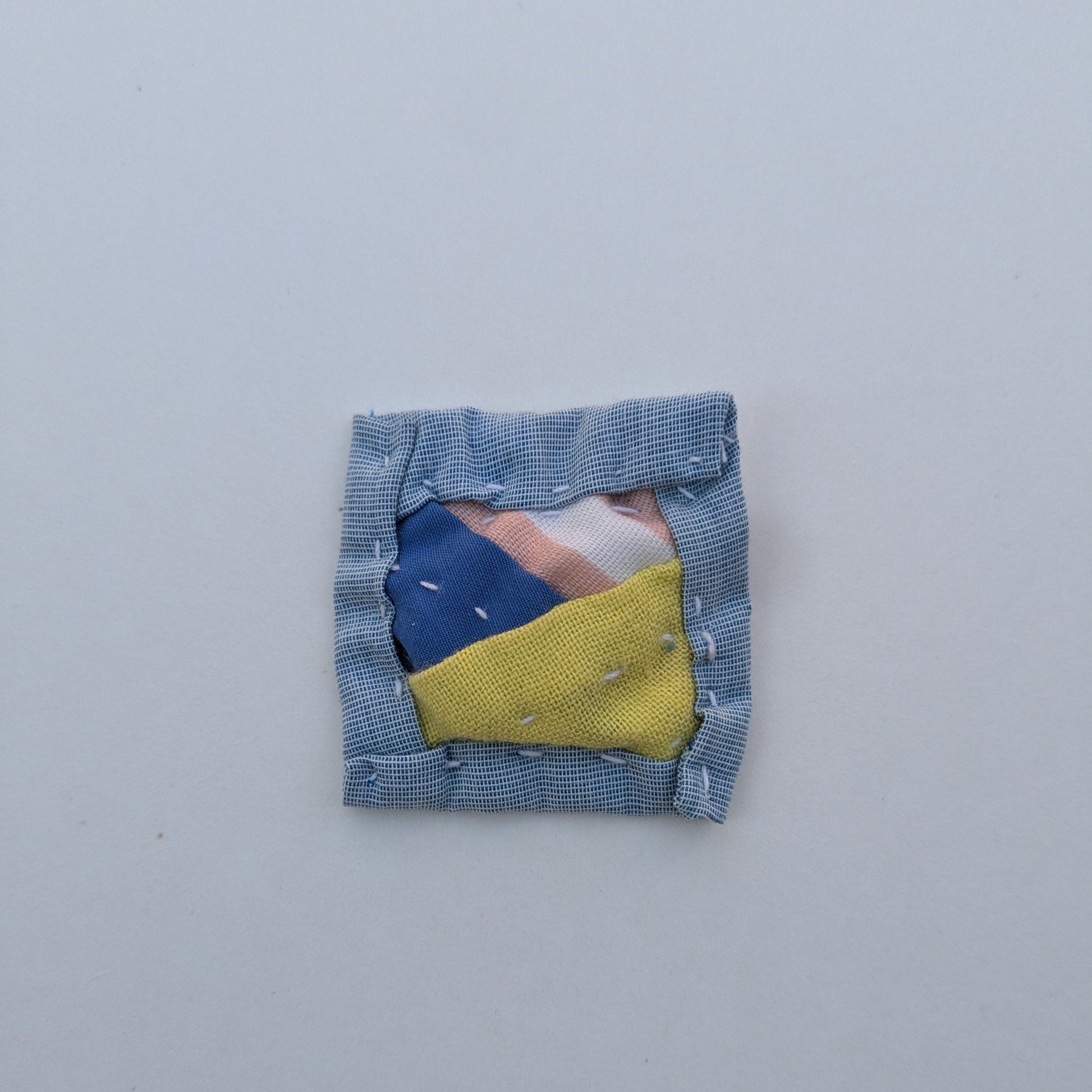 Square patchwork magnet with blue, pink, and bright green